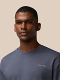 Close up of a man wearing a pewter colored Castore crew neck cotton T shirt.