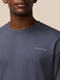Chest level shot of a man in a pewter crew neck cotton T shirt with Castore logo on the chest.