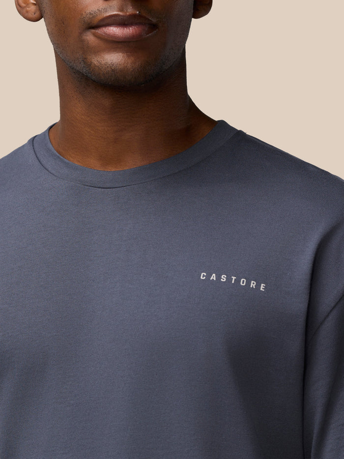 Chest level shot of a man in a pewter crew neck cotton T shirt with Castore logo on the chest.