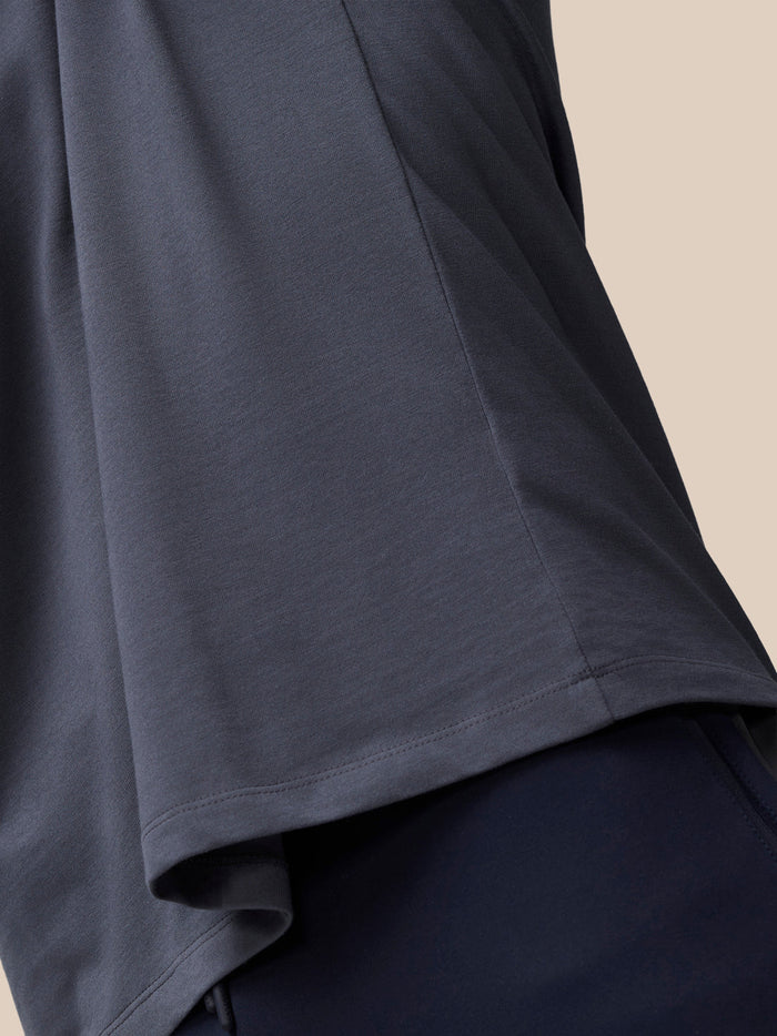 Close up of the lower side of the pewter Castore T shirt showing fabric drape and hem seam.