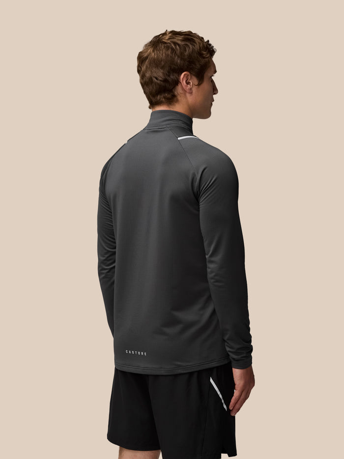 Three quarter view of male model wearing charcoal Apex Training Winterised 1/4 Zip Top with logo at the hem