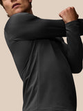 Front view of a model wearing black Apex Thermal Winterised ¼ zip top with a white zipper line, reflective shoulders and Castore logo on the chest