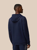 Back view of a man wearing a navy Flex Thermo Hoodie with the hood down against a beige background.