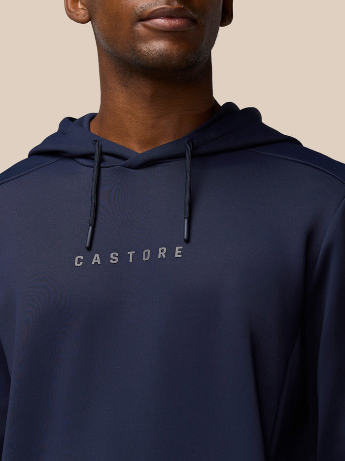 Close-up of a navy hoodie showing drawstrings and the Castore logo across the chest.