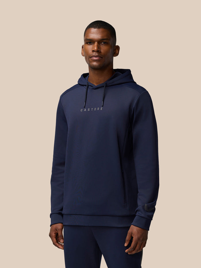 Front view of a man wearing navy Flex Thermo Hoodie with hood down and Castore logos on chest