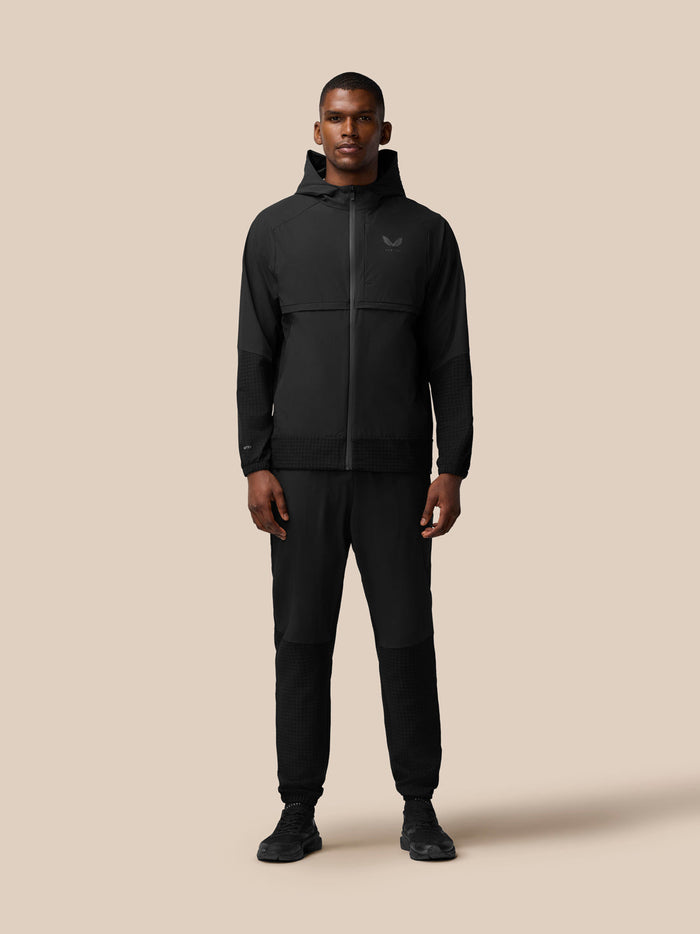Male model wearing black Flex Winterised woven jacket with hood, front zip and zip pockets, Castore logo on left chest
