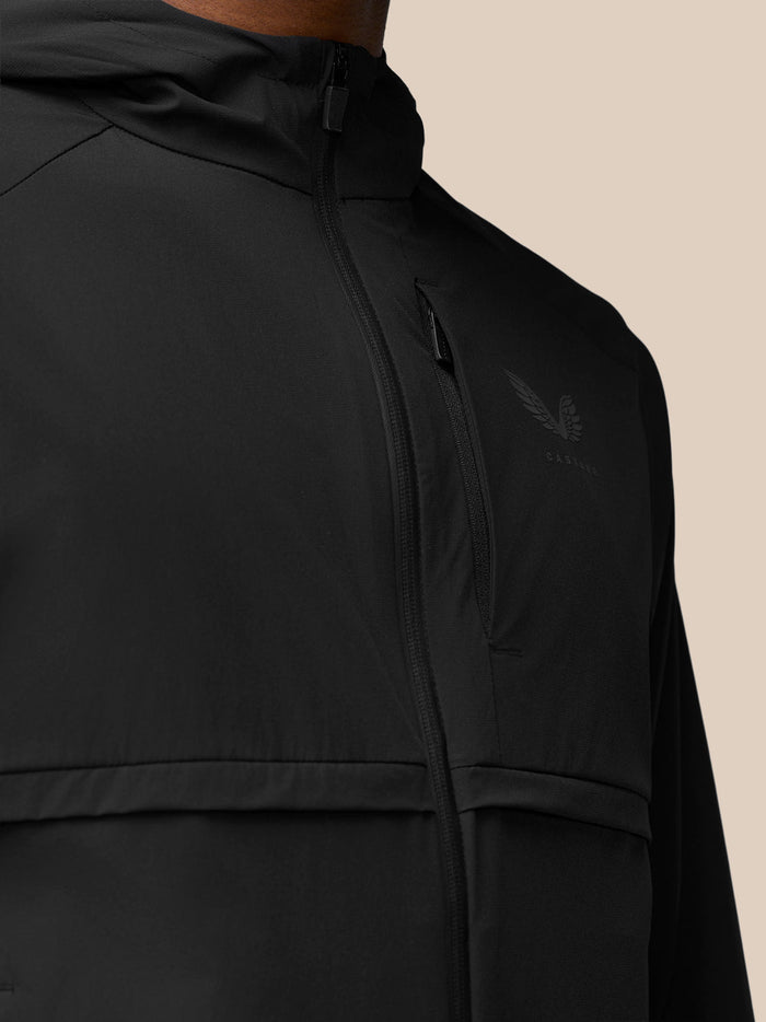 Close up of black jacket upper torso with a front zipper and Castore emblem on left chest
