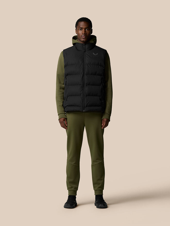 Full body shot of a man wearing a black ProTek puffer gilet over olive sleeves with front zip and zip pockets.