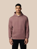 Male model wearing a mauve overhead hoodie with hood down and small Castore logo on the chest