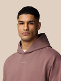 Front view of a man wearing a mauve hoodie with hood down and a CASTSTORE logo on the chest