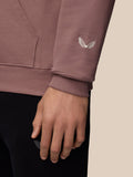 Close-up of the mauve hoodie sleeve showing a white Castore wing emblem embroidery near the cuff.