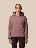 Female model wearing a mauve hoodie with a front kangaroo pocket and small logo on the chest