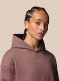 Close-up of a model wearing the mauve Adapt Lifestyle Hoodie with braided hair and Castore embroidery on the chest.