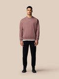 Full body shot of a male model wearing a mauve oversized ADAPT lifestyle sweatshirt with a left sleeve Castore wings logo.