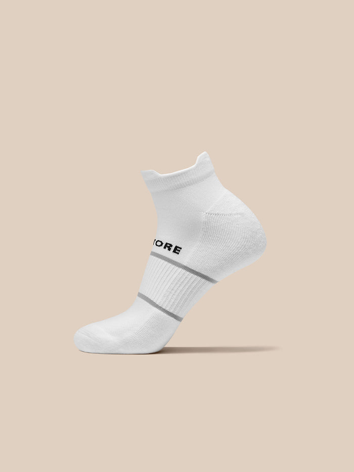 White ankle sock with Castore logo and grey stripes displayed on a beige background