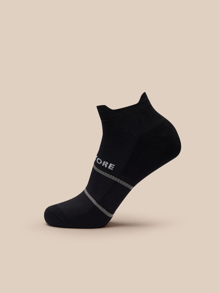 Black athletic sock with grey stripes and Castore branding against a beige background
