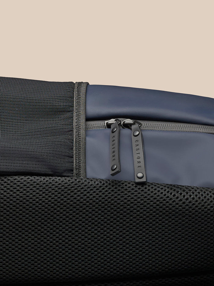 Close-up of navy backpack zipper pulls and mesh lower panel.