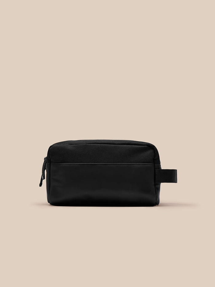 Black Castore wash bag with side strap and front zip pocket viewed from the front