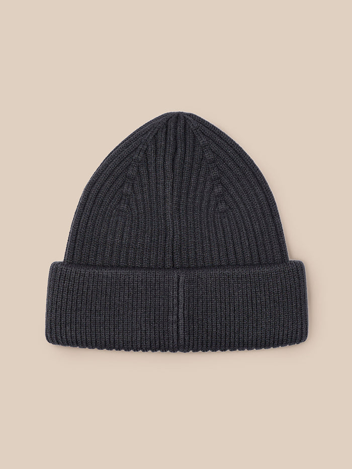 Close up of dark grey ribbed beanie with folded cuff and Castore patch.