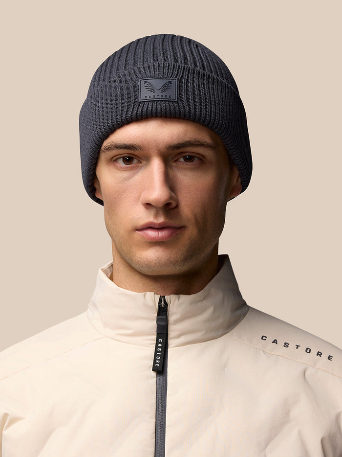 Male model wearing dark grey ribbed Castore Active Beanie with front logo patch.