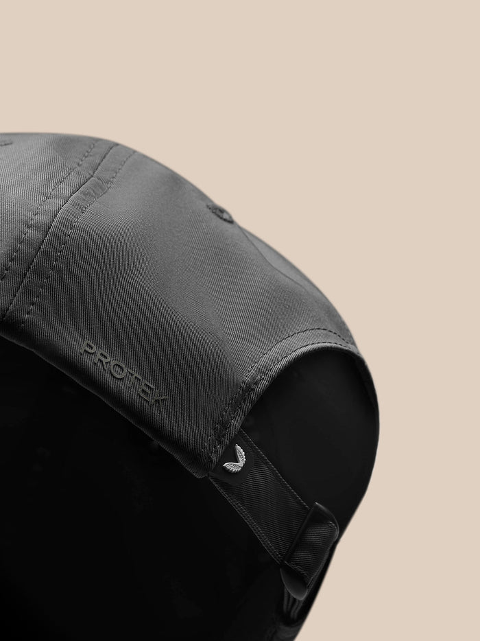 Close-up of back of gunmetal cap showing adjustable strap buckle and PROTEK badge.