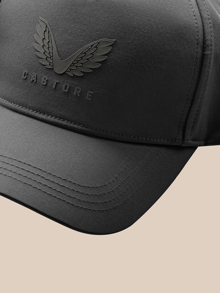 Close up of a gunmetal Castore cap with embossed wing logo on the front panel and stitched brim