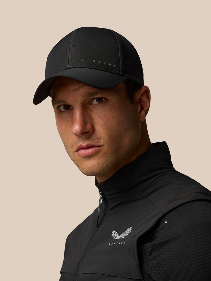 Male model wearing a black Castore cap in a studio shot.