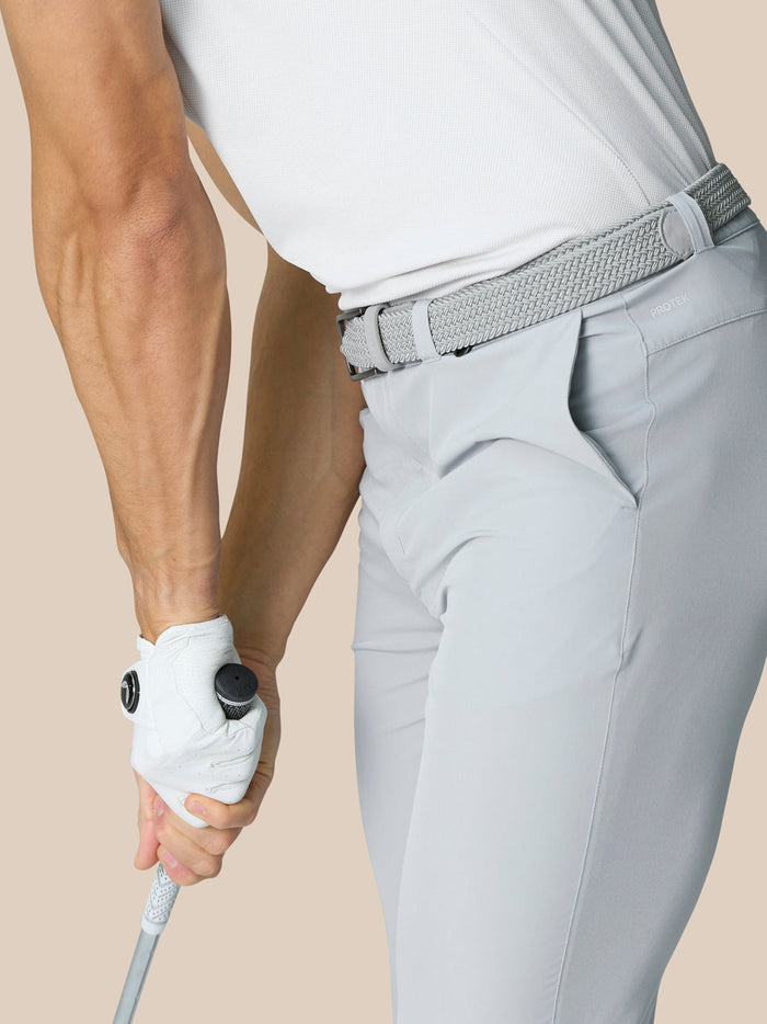 Side view of a model wearing light grey ProTek golf trousers with a braided belt.