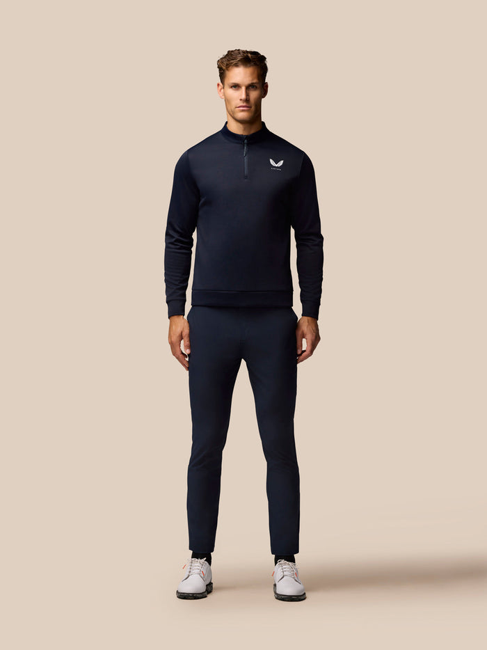 Full-length view of a male model in navy golf top and trousers with white sneakers.