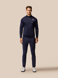 Full length model wearing navy golf trousers with a matching navy top and Castore branding on the thigh