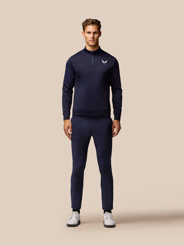 Full length model wearing navy golf trousers with a matching navy top and Castore branding on the thigh
