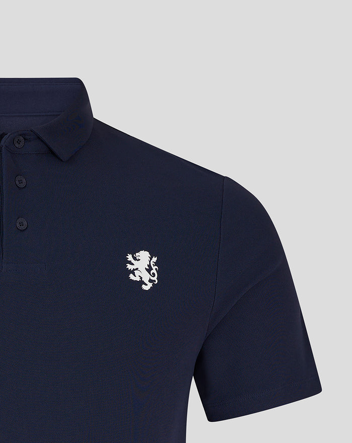 Close up of navy golf polo showing collar and three button placket with white crest on chest.