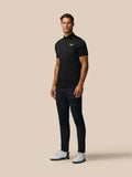 Male model wearing black Pinnacle Pique Stripe Polo with subtle horizontal stripes and white Castore logo.