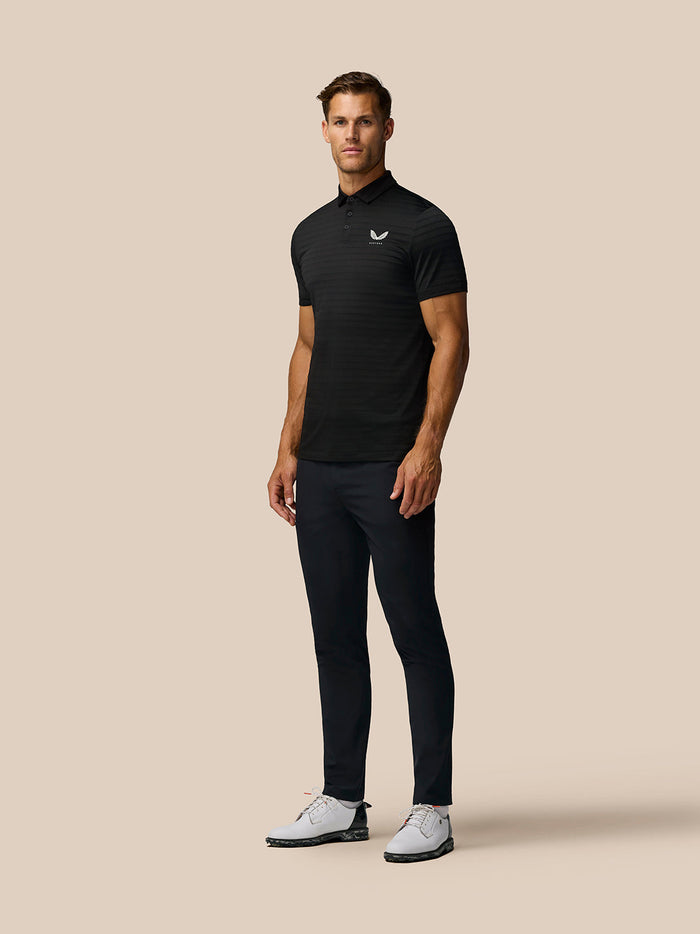 Male model wearing black Pinnacle Pique Stripe Polo with subtle horizontal stripes and white Castore logo.