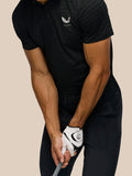 Side view of a golfer wearing a black striped polo with Castore logo on the upper back