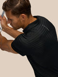 Back view of a golfer in a black striped polo with Castore branding on the upper back