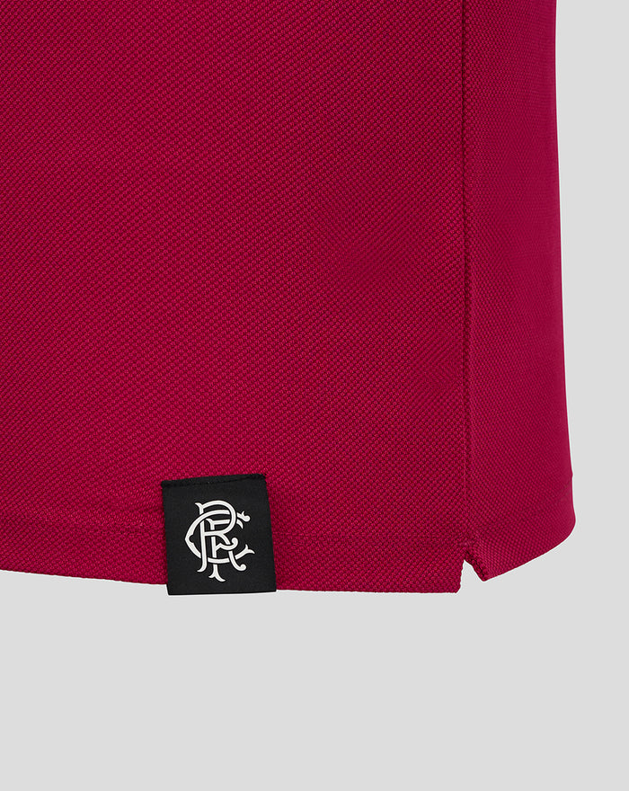 Hem detail of the maroon polo with a black tag displaying a white Castore logo.