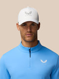 Close-up of a man wearing a white Castore cap and cool blue Golf Club Classic 1/4 Zip Top with funnel collar