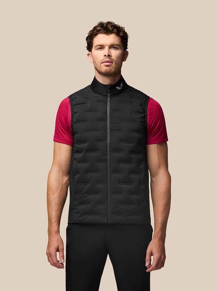 Male model wearing black Golf Pinnacle gilet with stand collar over a magenta short sleeve shirt and front zipper.