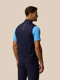 Back view of a man wearing a navy Pinnacle gilet with light blue sleeves and Castore branding along the upper back.