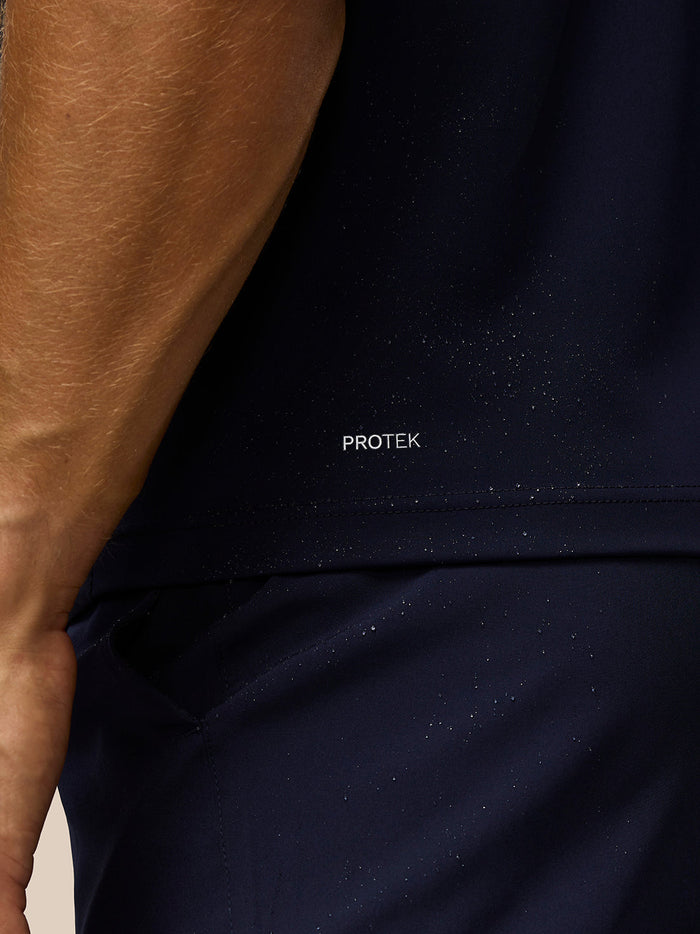 Close-up of dark navy Pinnacle gilet fabric with Protek branding and moisture specks