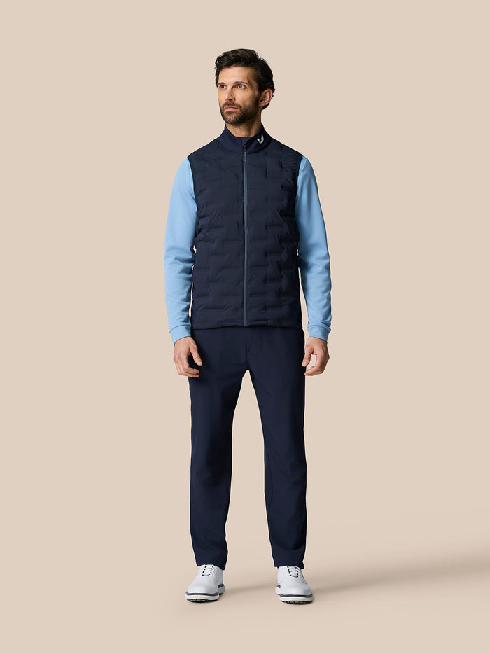 Full-body shot of a man in the Pinnacle Gilet with a light-blue top, navy pants and white shoes