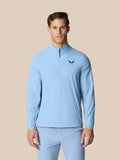 Front view of a man wearing a sky blue golf jacket with half zip and high funnel neckline, Castore logo on the chest.