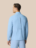 Back view of sky blue golf jacket with Castore logo on the lower back.