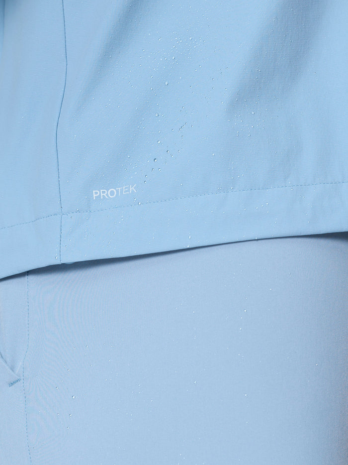 Close up of sky blue golf jacket fabric with water droplets and ProTek branding.