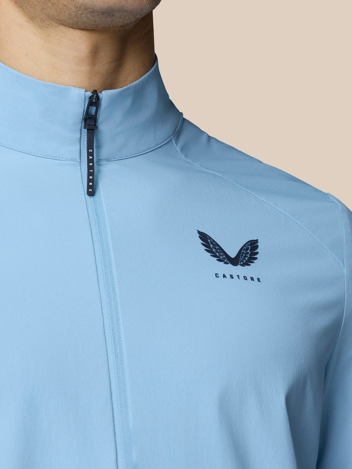 Back view detail of sky blue golf jacket showing vertical back vent and Castore logo.