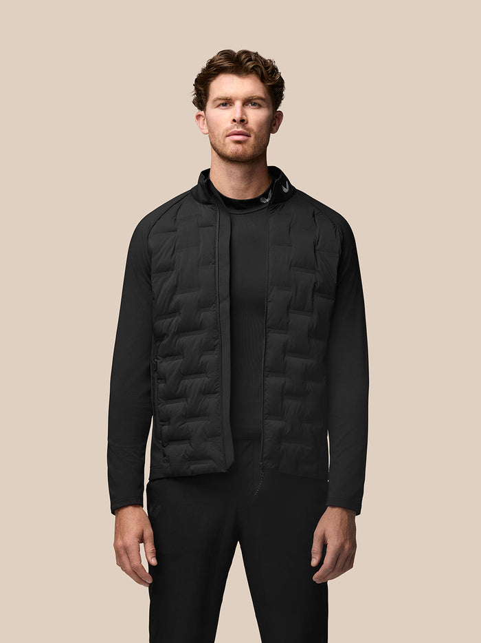 Male model wearing black Pinnacle Golf Jacket with quilted front panels and stand collar.