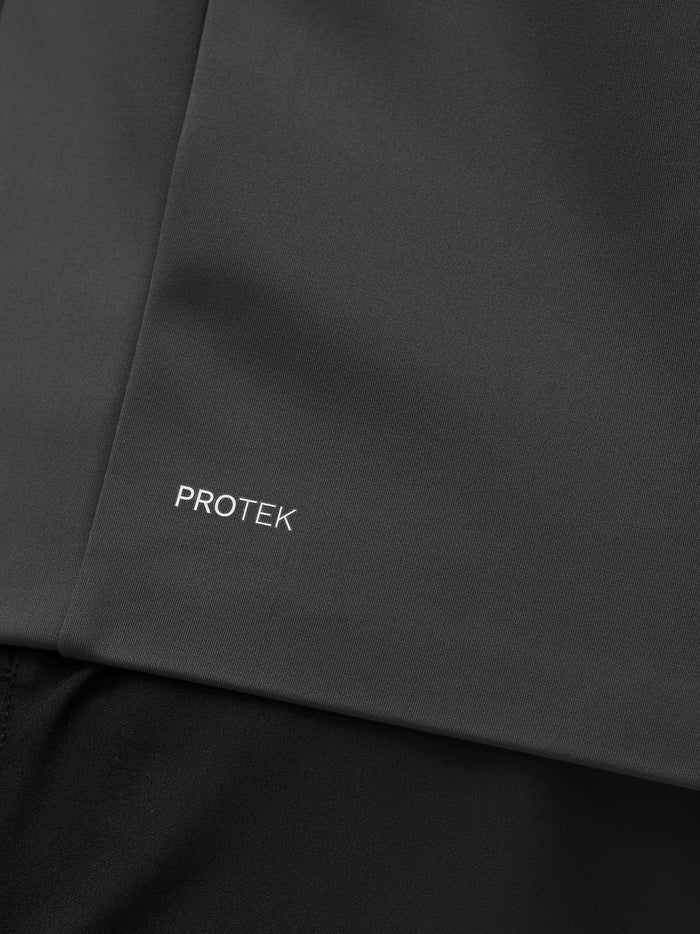 Close-up of dark jacket fabric showing Protek branding near the hem.