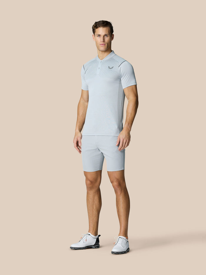 Male model wearing light grey Pinnacle Golf LVS polo with matching shorts, showcasing engineered knit polo.