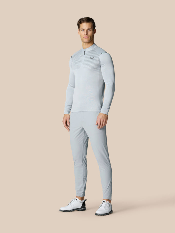Full body shot of male model in matching light grey Pinnacle LVS 1/4 zip top and pants with white golf shoes